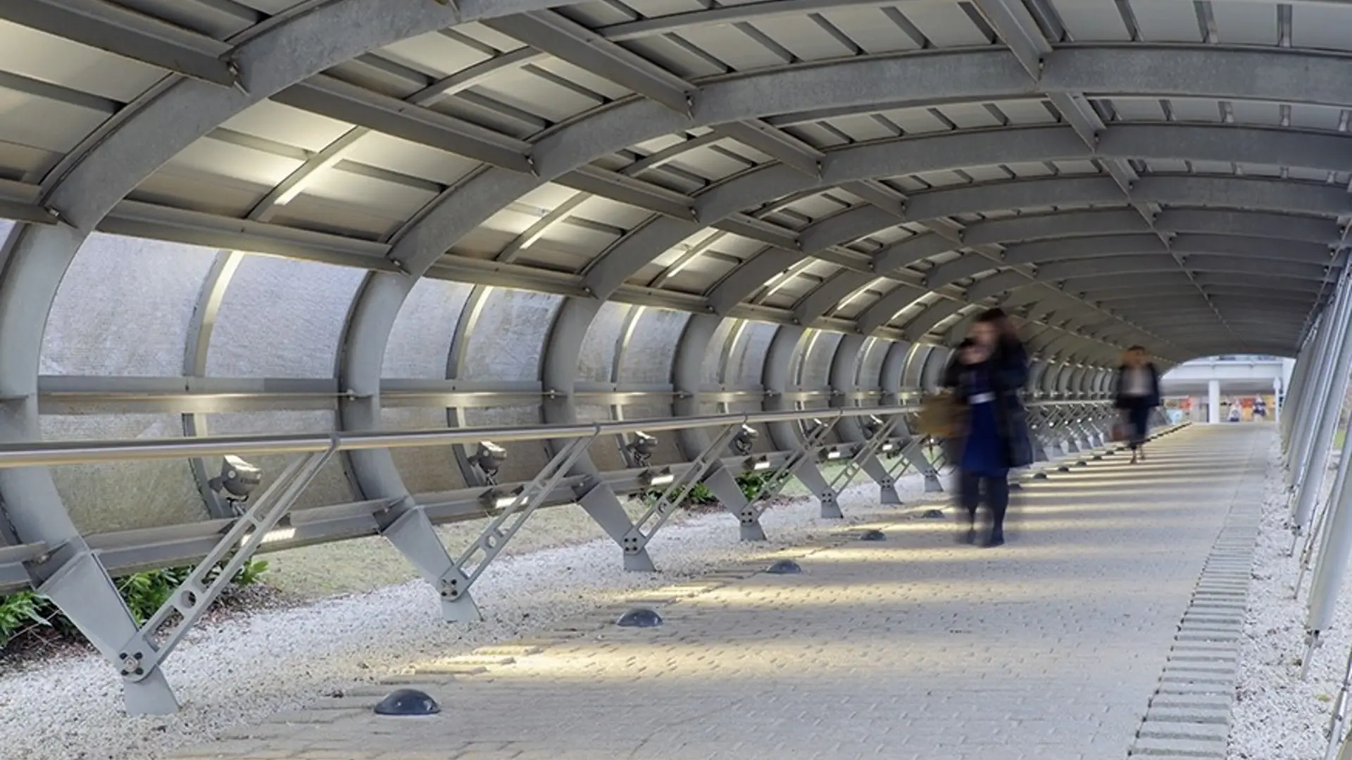 A woman walks through a metal tunnel that is lit by Tamlite's CITY Range. Creating More Sustainable Cities: How Tamlite’s CITY Range Offers a Complete Urban Lighting Solution