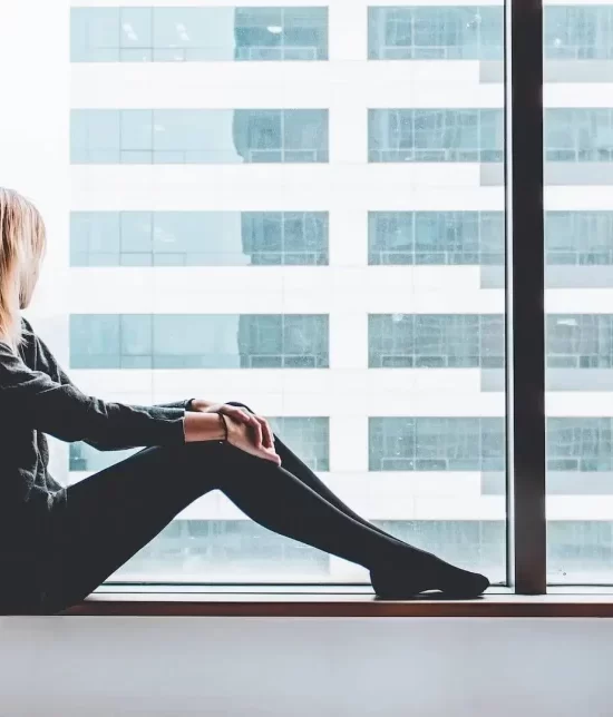 Woman sat on a window ledge looking out